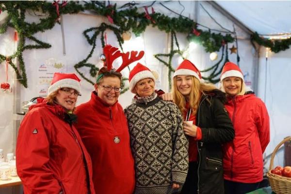 Menschen mit Weihnachtsmützen lächeln ins Bild