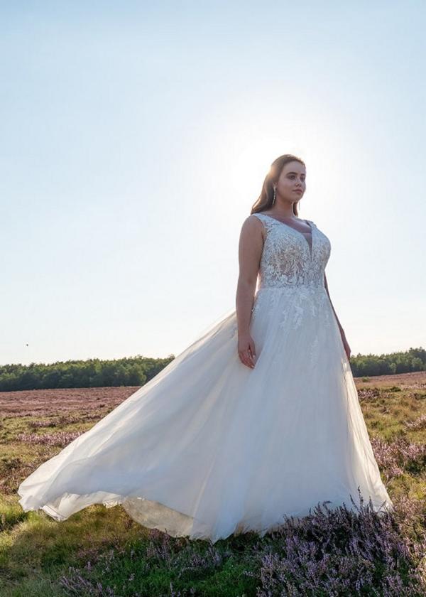 Foto Braut steht auf Wiese vor blauem Himmel. Kleid von Amelie Groß von Wundervoll Braut aus Hannover Isernhagen