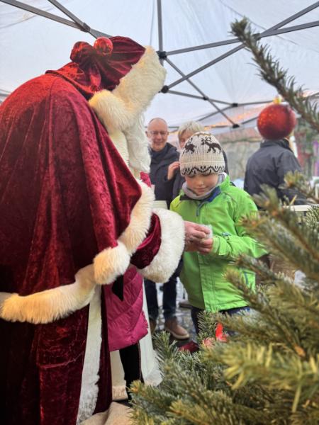 Weihnachtsmann beschenkt ein Kind auf dem Weihnachtsmarkt in Bothfeld.