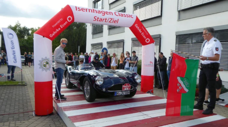 Ein Oldtimer steht am Start umringt von Menschen.